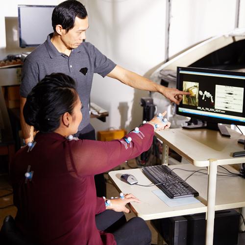 A wheelchair user and man point at a screen