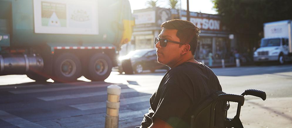 Wheelchair user sits by a pedestrian crossing